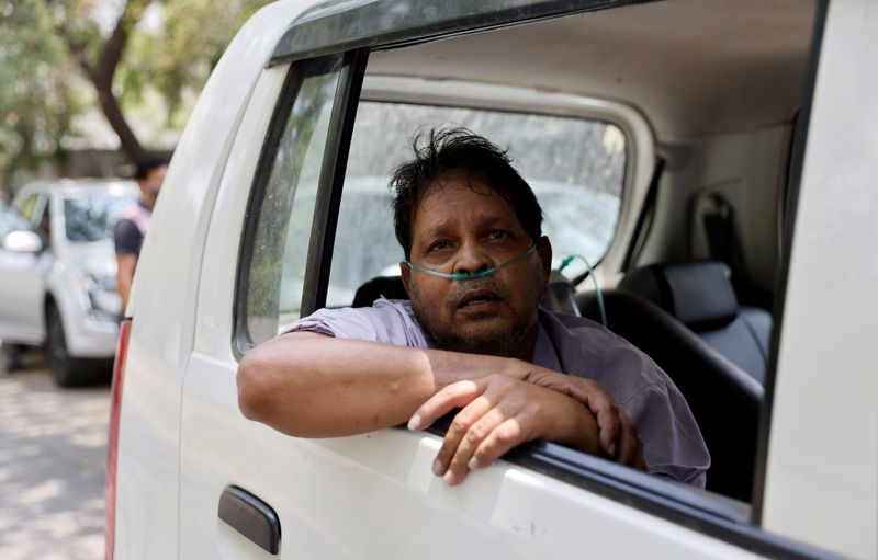 &copy; Reuters. Vijay Gupta with breathing problem sits inside a car as he waits to get admission at a COVID-19 hospital for treatment, in Ahmedabad