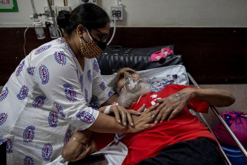 © Reuters. A man suffering from the coronavirus disease (COVID-19) is comforted by his daughter as he receives treatment inside the casualty ward at a hospital in New Delhi