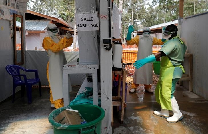 © Reuters. FILE PHOTO: Moise Vaghemi (L), 33, an Ebola survivor who works as a nurse, gets dressed in a protective suit as he prepares to start his shift at an  Ebola treatment centre in Katwa