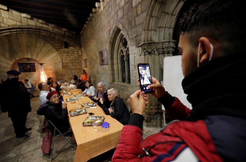 &copy; Reuters. رجل يلتقط صورة بهاتفه المحمول لأفراد يتناولون الافطار في كنيسة "سانتا آنا" في برشلونة يوم 28 أبريل نيسان 2021. تصوير: البرت خيا - رويترز. 