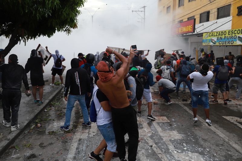 © Reuters. 　コロンビアで政府の税制改革に対する抗議デモが連日各地で行われ、ドゥケ大統領は法案取り下げを表明する事態に追い込まれた。写真はカリでのデモ隊と治安部隊の衝突。３日撮影（２０２１年　ロイター／Juan Bautista） 