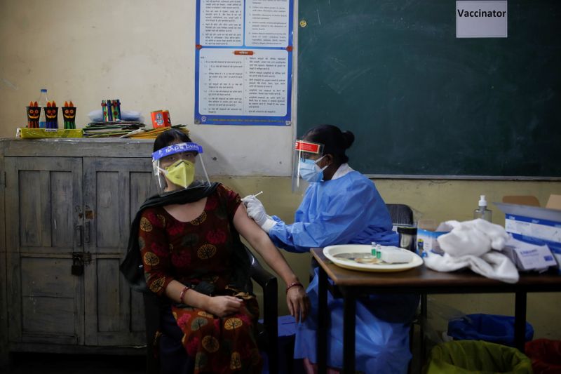 © Reuters. A healthcare worker gives a dose of COVISHIELD, a coronavirus disease (COVID-19) vaccine manufactured by Serum Institute of India, to a woman inside a classroom of a school, which has been converted into a temporary vaccination centre, in New Delhi, India, May 4, 2021. REUTERS/Adnan Abidi