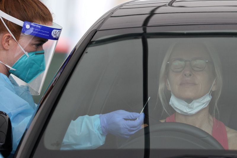 &copy; Reuters. FILE PHOTO: A medical worker swabs a member of the public at a drive-through COVID-19 testing centre in Sydney
