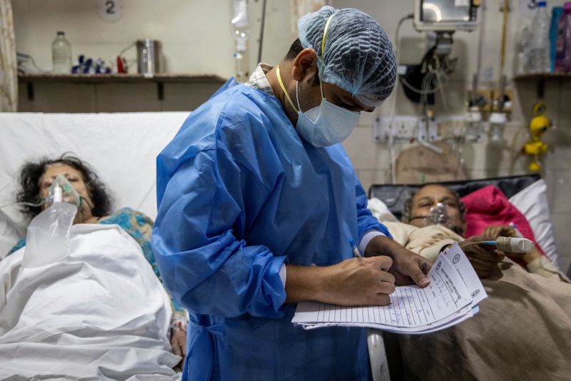 &copy; Reuters. Rohan Aggarwal, 26, a resident doctor treating patients suffering from the coronavirus disease (COVID-19), writes down notes during his 27-hour shift at Holy Family Hospital in New Delhi, India, May 1, 2021. "If a patient has a fever, and I know he's sick