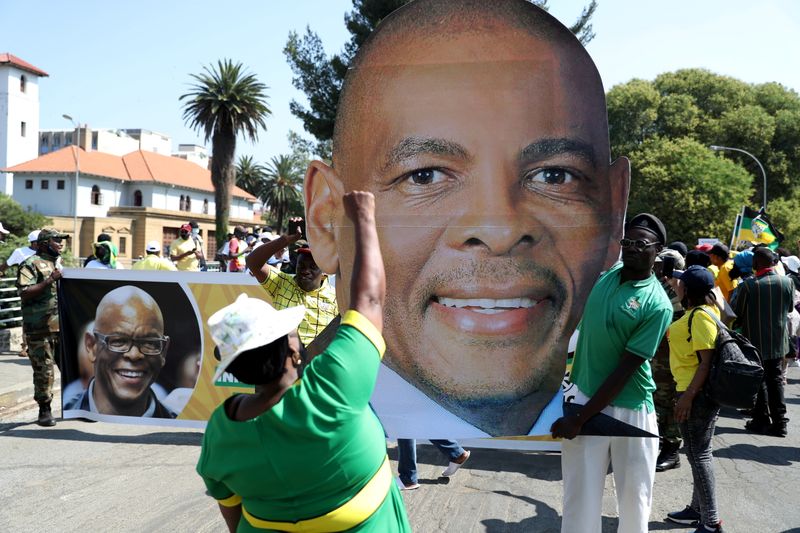 &copy; Reuters. FILE PHOTO: A supporter gestures in front of a picture of Ace Magashule, the secretary general of South Africa&apos;s ruling African National Congress, ahead of his court appearance, at the Bloemfontein high court in the Free State province