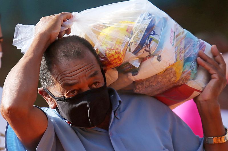 &copy; Reuters. Homem carrega cesta básica distribuída pelo "G10 das Favelas", bloco de líderes e empreendedores das favelas, em Heliópolis, região sul de São Paulo (SP)
14/04/2021 REUTERS/Carla Carniel