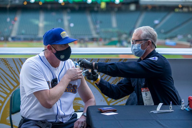 &copy; Reuters. FILE PHOTO: May 4, 2021; Seattle, Washington, USA; Seattle Fire Department EMT Bill Allemann gives Chris Hoffman, of Kent, Washington a Johnson & Johnson Covid-19 vaccine during batting practice before a game between the Seattle Mariners and Baltimore Ori