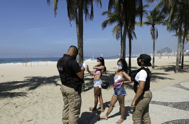 &copy; Reuters. Guarda municipal multa duas mulheres que não usavam máscara na Praia do Leme, no Rio de Janeiro
20/03/2021 REUTERS/Ricardo Moraes