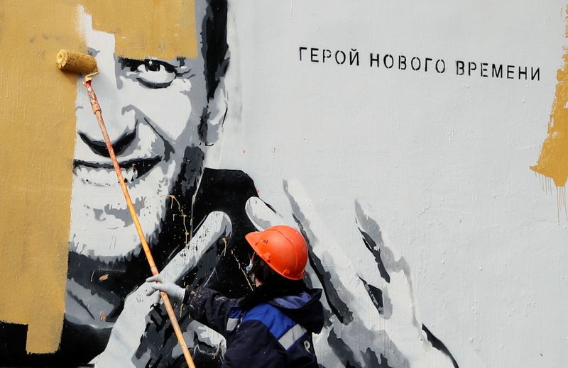 © Reuters. A worker paints over a graffiti depicting Alexei Navalny in Saint Petersburg