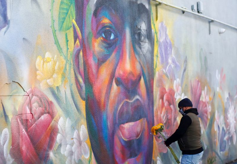 &copy; Reuters. FILE PHOTO: A man places flowers at a mural of George Floyd after the verdict in the trial of former Minneapolis police officer Derek Chauvin, found guilty of the death of Floyd, in Denver, Colorado, U.S., April 20, 2021. REUTERS/Kevin Mohatt