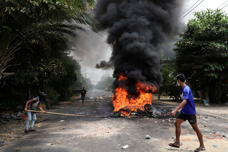 © Reuters. متظاهر ضد الانقلاب العسكري في ميانمار يسير أمام اطارات مشتعلة في يانجون يوم 30 مارس اذار 2021. تصوير:رويترز.