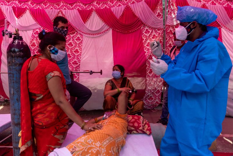 &copy; Reuters. A woman surrounded by her relatives receives oxygen support for free at a Gurudwara in Ghaziabad