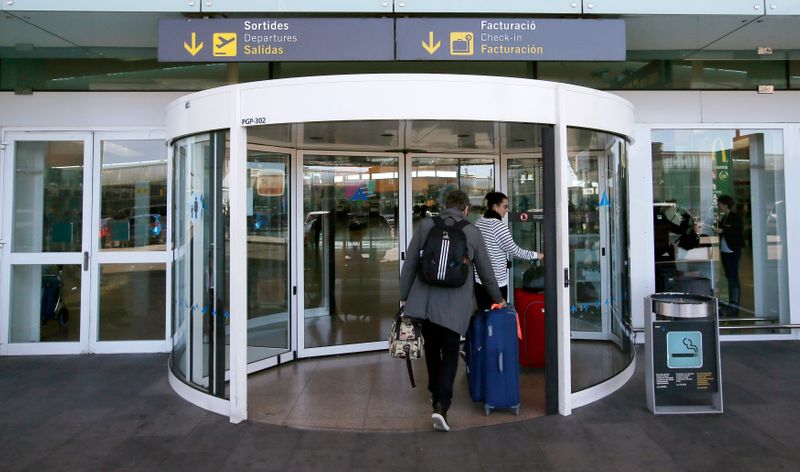 &copy; Reuters. FOTO DE ARCHIVO: Dos pasajeros con maletas entran al eropuerto de Barcelona