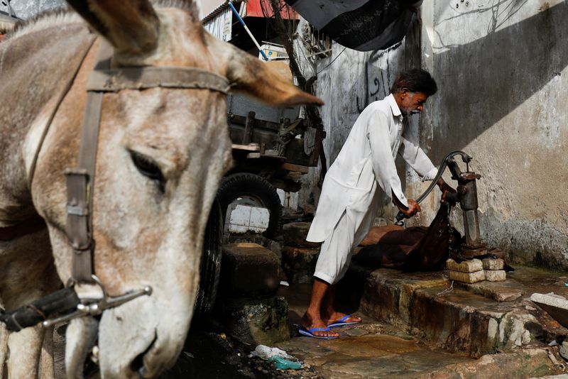 &copy; Reuters. السقاء محمد رمضان (60 عاما) يضخ الماء في قربة كبيرة من جلد الماعز قبل أن يمشي بها في زقاق لتوصيل الماء إلى السكان في كراتشي  يوم 23 أبريل نيسان 202