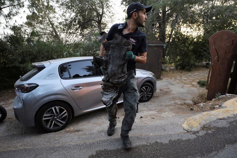 © Reuters. شرطي إسرائيلي يحمل بقايا صاروخ أطلقته حماس سقط بالقرب من القدس يوم الاثنين. تصوير: عمار عوض - رويترز.
