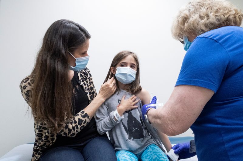 © Reuters. Marisol Gerardo, 9, is held by her mother as she gets the second dose of the Pfizer coronavirus disease (COVID-19) vaccine during a clinical trial for children at Duke Health in Durham, North Carolina, U.S., April 12, 2021. Shawn Rocco/Duke Health/Handout via REUTERS