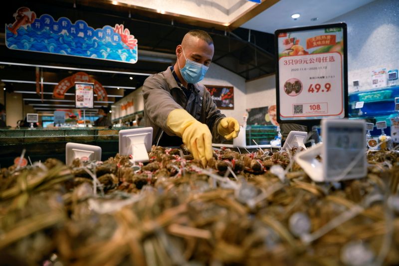 &copy; Reuters. FILE PHOTO: A staff member lays out seafood at a supermarket following an outbreak of the coronavirus disease (COVID-19) in Beijing, China November 11, 2020. REUTERS/Thomas Peter