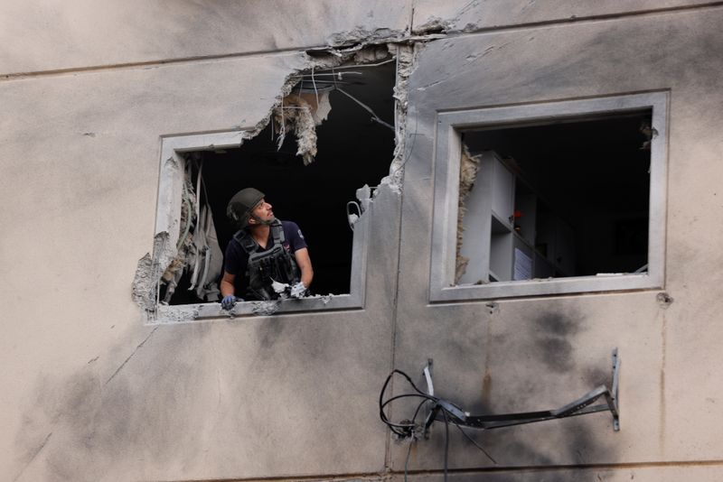 &copy; Reuters. شرطي إسرائيلي ينظر إلى الأضرار التي لحقت بمبنى نتيجة لصاروخ أطلق من غزة في صورة التقطت في عسقلان يوم الثلاثاء. تصوير: أمير كوهين - رويترز.