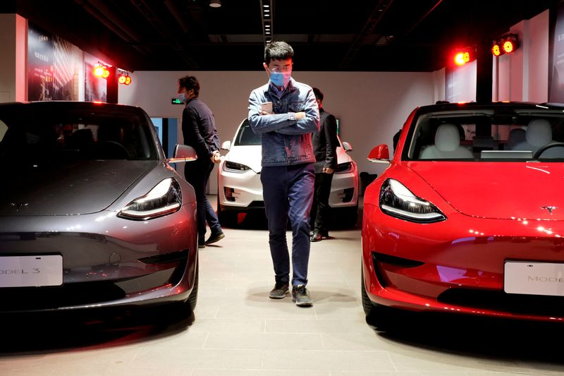 &copy; Reuters. FOTO DE ARCHIVO. Un hombre camina junto a los sedanes Tesla Model 3 y el vehículo utilitario deportivo Tesla Model X en una nueva sala de exposición de Tesla en Shanghái, China