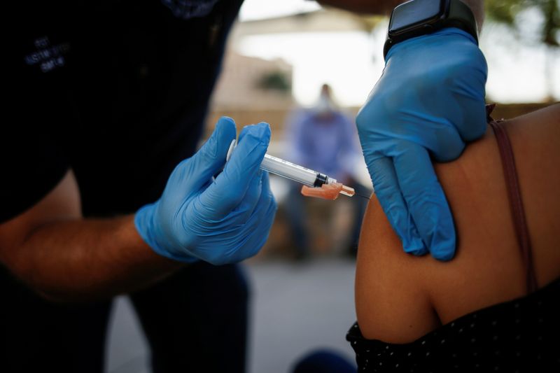 &copy; Reuters. FILE PHOTO: A healthcare worker from the El Paso Fire Department administers the Moderna vaccine against the coronavirus disease (COVID-19) at a vaccination centre near the Santa Fe International Bridge, in El Paso, Texas, U.S May 7, 2021. Picture taken M