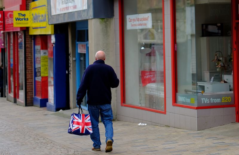 © Reuters. FILE PHOTO: A man carries a Union Jack themed shopping bag as he walks along an empty shopping street in Blackpool, Britain, March 9, 2021. REUTERS/Phil Noble/File Photo