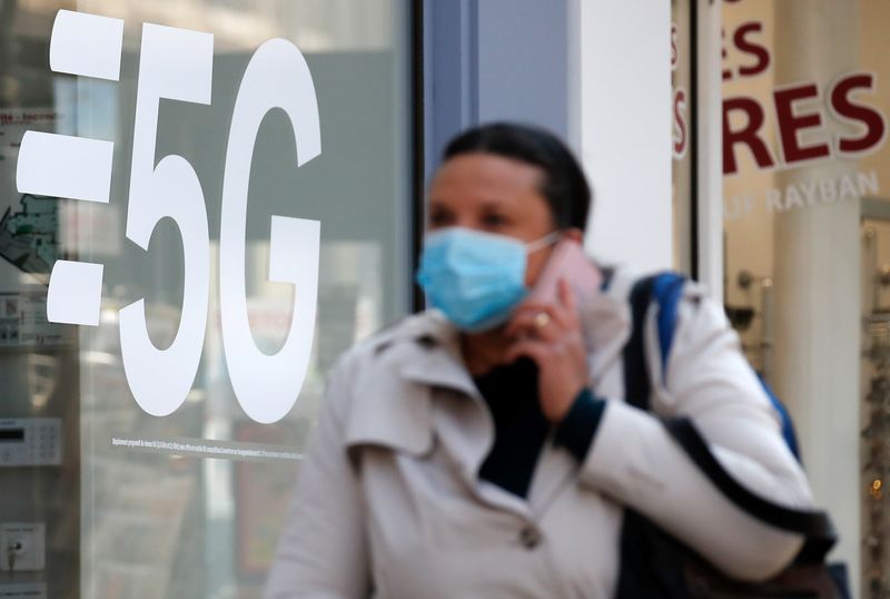 &copy; Reuters. A woman walks past a 5G data network sign at a mobile phone store in Paris