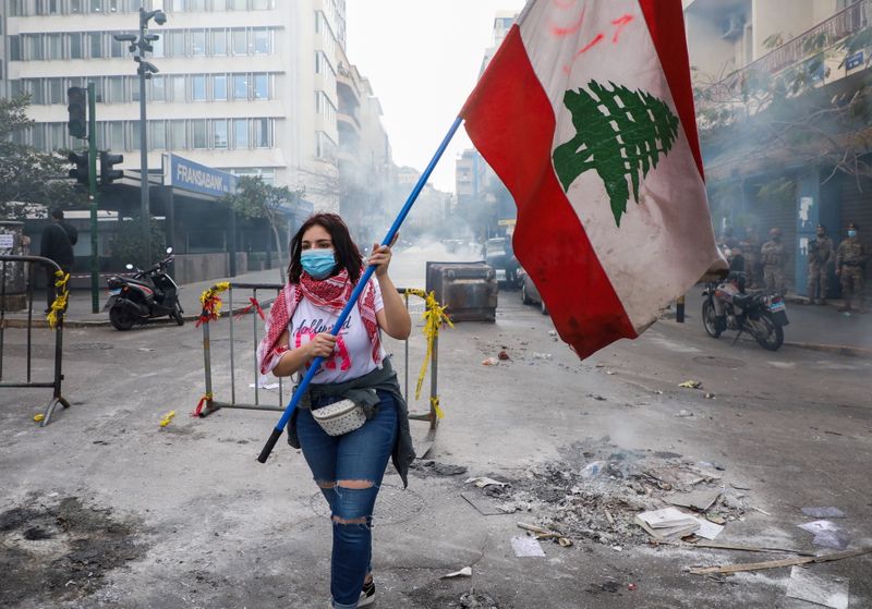 © Reuters. متظاهرة تحمل علم لبنان في بيروت بصورة من أرشيف رويترز.