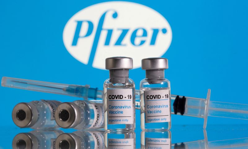 &copy; Reuters. IMAGEN DE ARCHIVO. Frascos con la etiqueta de "Vacuna COVID-19 Coronavirus" y una jeringa se ven frente al logo de Pfizer en esta ilustración tomada en febrero 9, 2021. REUTERS/Dado Ruvic