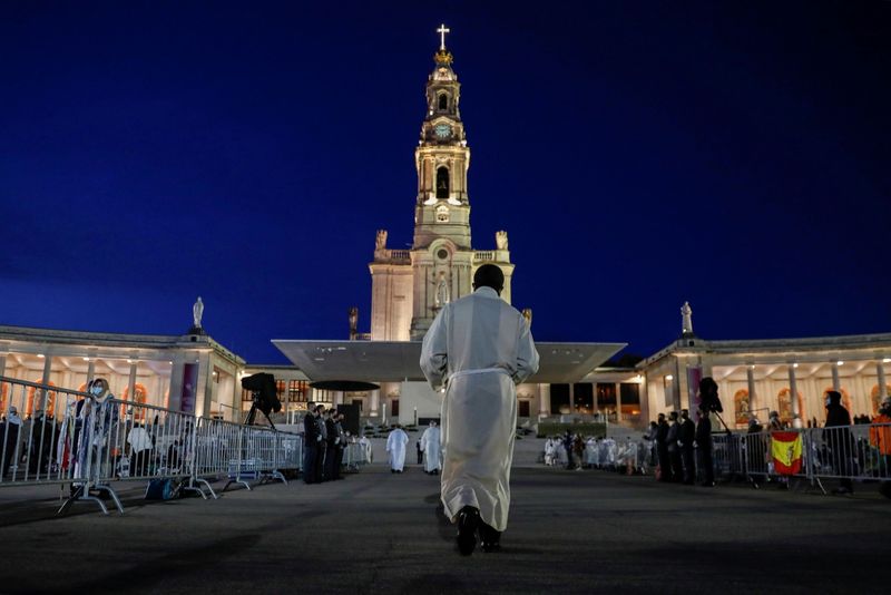 © Reuters. A member of the clergy walks during the 104th anniversary of the appearance of the Virgin Mary to three shepherd children at the Catholic shrine of Fatima