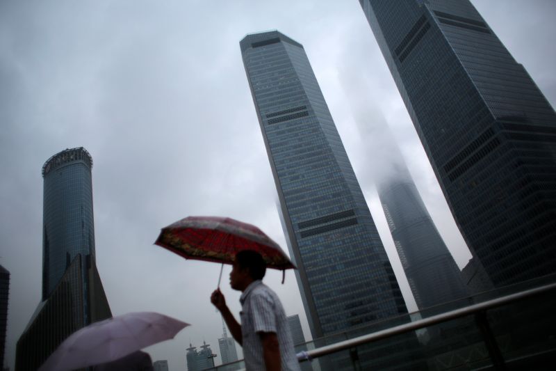 &copy; Reuters. FILE PHOTO: A man walks in the rain along the financial district of Pudong in downtown Shanghai August 18, 2014. REUTERS/Carlos Barria 