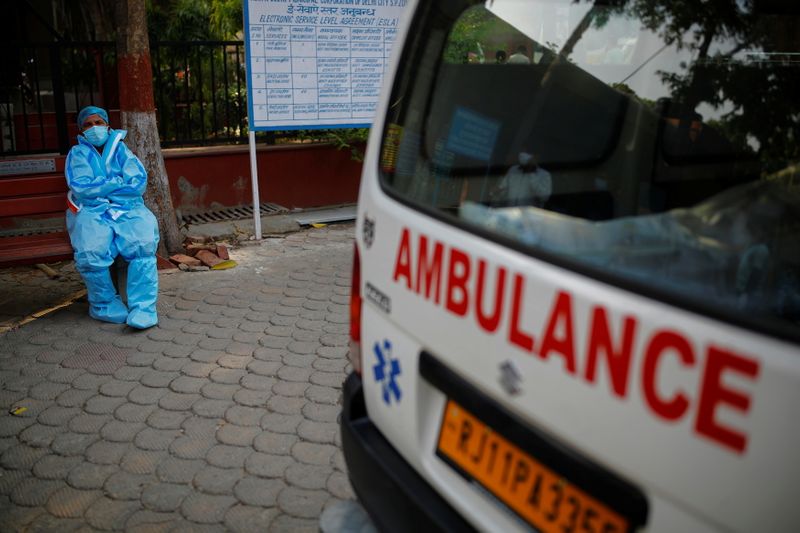 &copy; Reuters. A health worker rests as he sits next to his ambulance carrying a dead body of a victim who died due to the coronavirus disease (COVID-19), at a crematorium