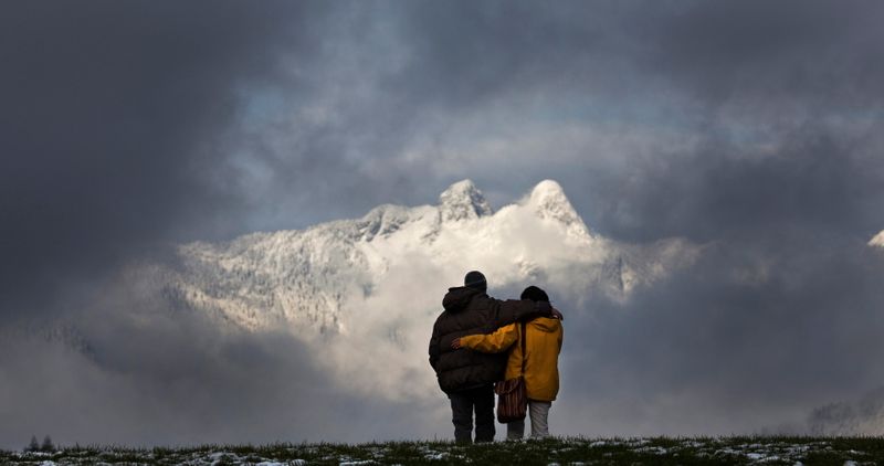 &copy; Reuters. A couple walks arm-in-arm while visiting Capilano Park as the Lions Gate Mountain is seen through the clouds in North Vancouver, British Columbia November 20, 2010. REUTERS/Andy Clark