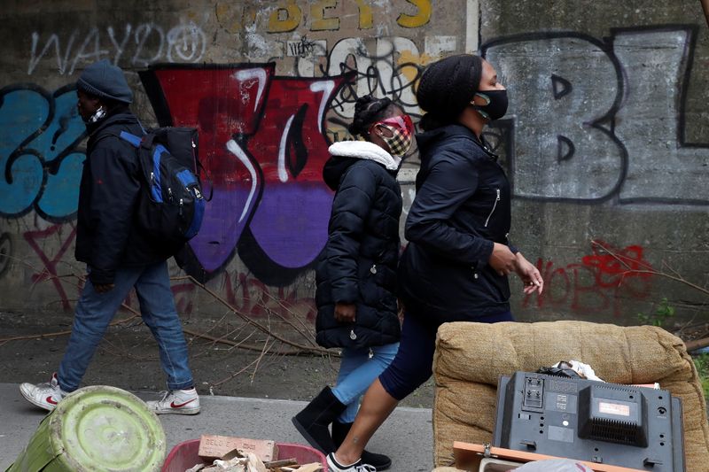 &copy; Reuters. FILE PHOTO: People wearing protective masks walk by a man not wearing a mask over his nose under the subway in the Brownsville section of the Brooklyn borough of New York City, U.S., May 3, 2021. REUTERS/Shannon Stapleton