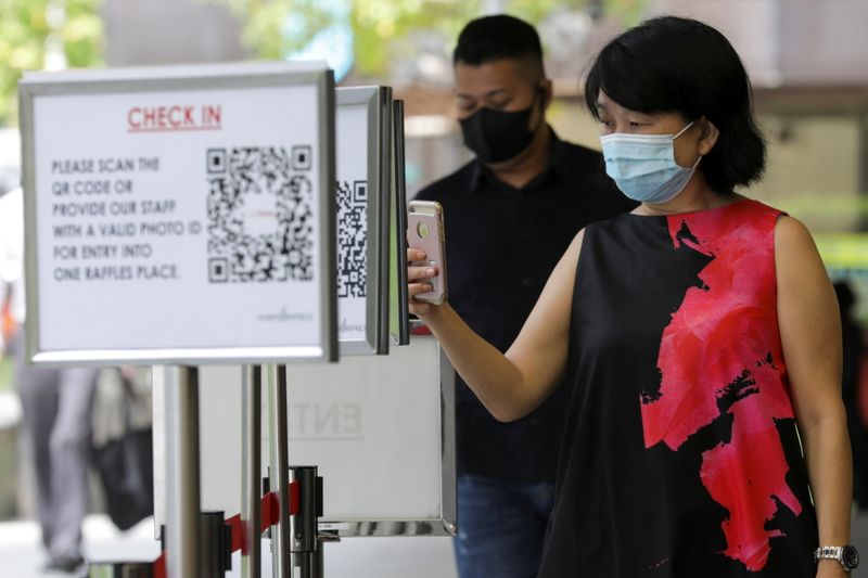 &copy; Reuters. Office workers scan a Safe Entry QR code to enter a mall, amid the coronavirus disease (COVID-19) outbreak in Singapore