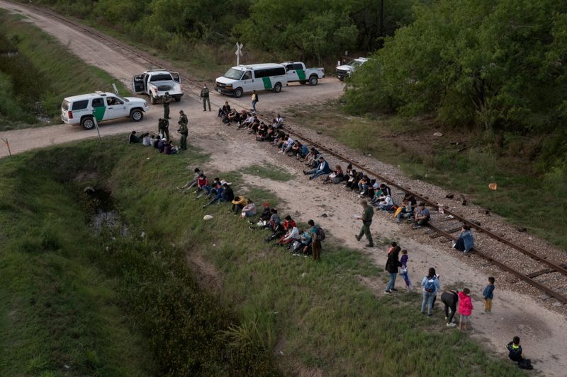 © Reuters. FILE PHOTO: Dozens of asylum-seeking migrants from Romania, Armenia, and Central America, including a group of unaccompanied minors, await to be transported to a U.S. border patrol processing facility after crossing the Rio Grande river into the United States from Mexico on a raft in La Joya, Texas, U.S., May 5, 2021. Picture taken with a drone. REUTERS/Adrees Latif/File Photo