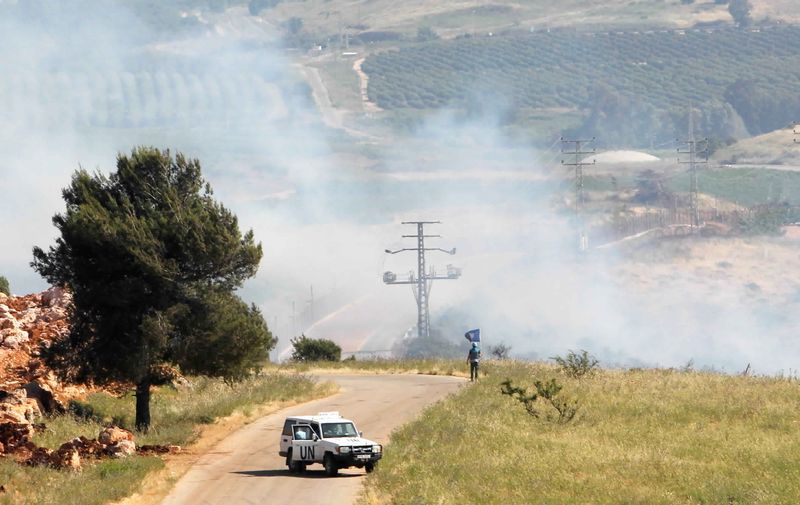 © Reuters. أحد أفراد قوة الأمم المتحدة المؤقتة في لبنان (اليونيفيل) يقف أثناء تصاعد الدخان في بلدة الخيام قرب الحدود مع اسرائيل يوم الجمعة. تصوير: عزيز طاهر-رويترز.