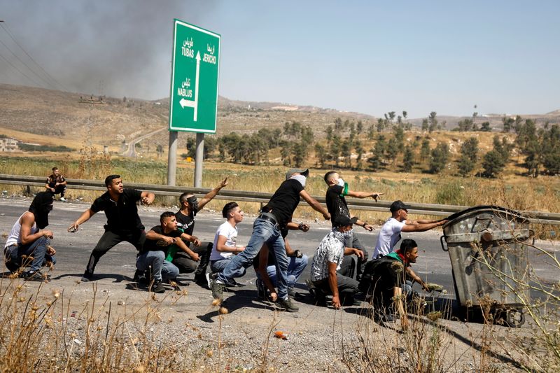© Reuters. متظاهرون فلسطينيون يقذفون القوات الاسرائيلية بالحجارة خلال احتجاجات قرب نقطة تفتيش بالقرب من نابلس بالضفة الغربية المحتلة يوم الجمعة. تصوير: رنين صوافطة-رويترز.
