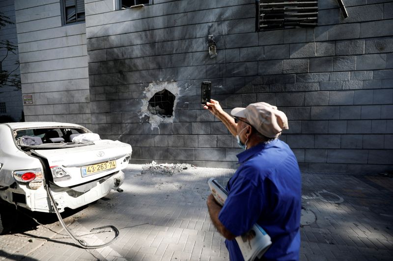 © Reuters. اسرائيلي يلتقط صورة بهاتفه المحمول لمبنى سكني في عسقلان باسرائيل يوم الجمعة عقب هجمات صاروخية من قطاع غزة. تصوير: أمير كوهين-رويترز.