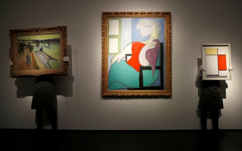 &copy; Reuters. FILE PHOTO: Employees pose for a photograph with "Le pont de Trinquetaille" by Vincent van Gogh, "Femme Assise Pres d'Une Fenetre (Marie-Therese)" by Pablo Picasso and "Composition: No. II with Yellow, Red and Blue" by Piet Mondrian, at Christie's gallery