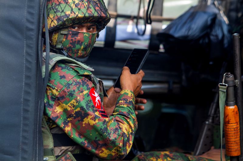 &copy; Reuters. FILE PHOTO: A soldier uses a mobile phone as he sit inside a military vehicle outside Myanmar's Central Bank during a protest against the military coup, in Yangon, Myanmar, February 15, 2021. REUTERS/Stringer/File Photo