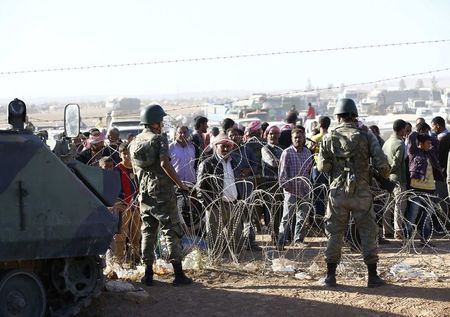 © Reuters. Turkish soldiers stand guard as Syrian Kurds wait behind a border fence near the southeastern town of Suruc in Sanliurfa province