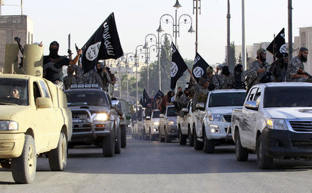 © Reuters. Militant Islamist fighters parade on military vehicles along the streets of northern Raqqa province