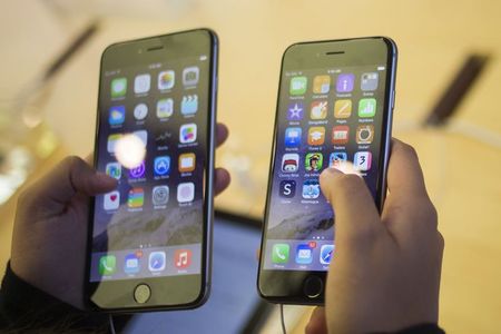 © Reuters. A customer holds an iPhone 6  and iPhone 6 Plus after the phones went on sale at the Fifth Avenue Apple store in New York