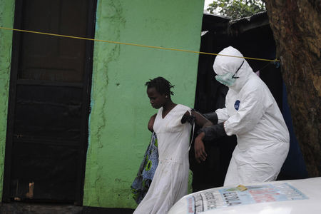 © Reuters. Health worker brings a woman suspected of having contracted the Ebola virus to an ambulance in Monrovia