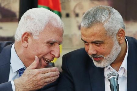 © Reuters. Senior Fatah official Azzam Al-Ahmed speaks with head of the Hamas government Ismail Haniyeh as they announce a reconciliation agreement during a news conference in Gaza City