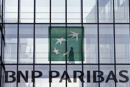 © Reuters. An employee walks behind the logo of BNP Paribas in a company's building in Issy-les-Moulineaux, near Paris