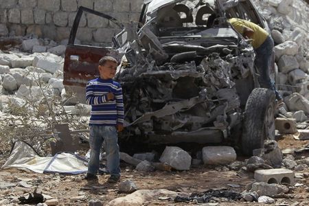 © Reuters. Meninos observam carro destruído por ataque aéreo dos EUA em Kfredrian, na Síria, segundo ativistas