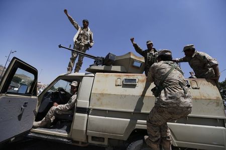 © Reuters. Members of the presidential guard force board a patrol vehicle positioned at a checkpoint near the Presidential Palace in Sanaa