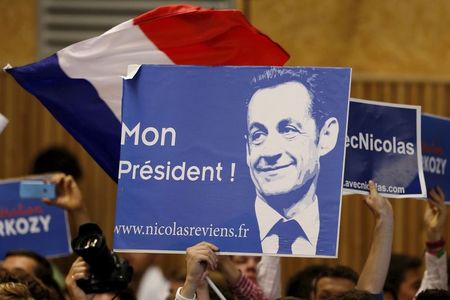 © Reuters. Political supporters hold a poster for France's former president Sarkozy who attends a political rally as he campaigns for the leadership of the UMP political party in Lambersart