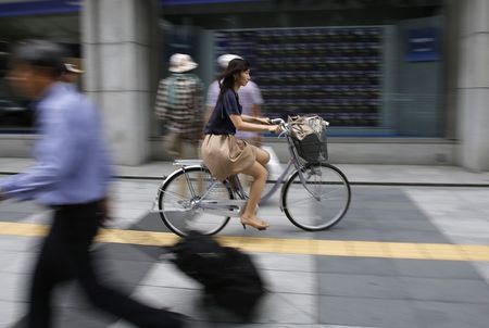 © Reuters. A woman cycles in front of a brokerage in Tokyo